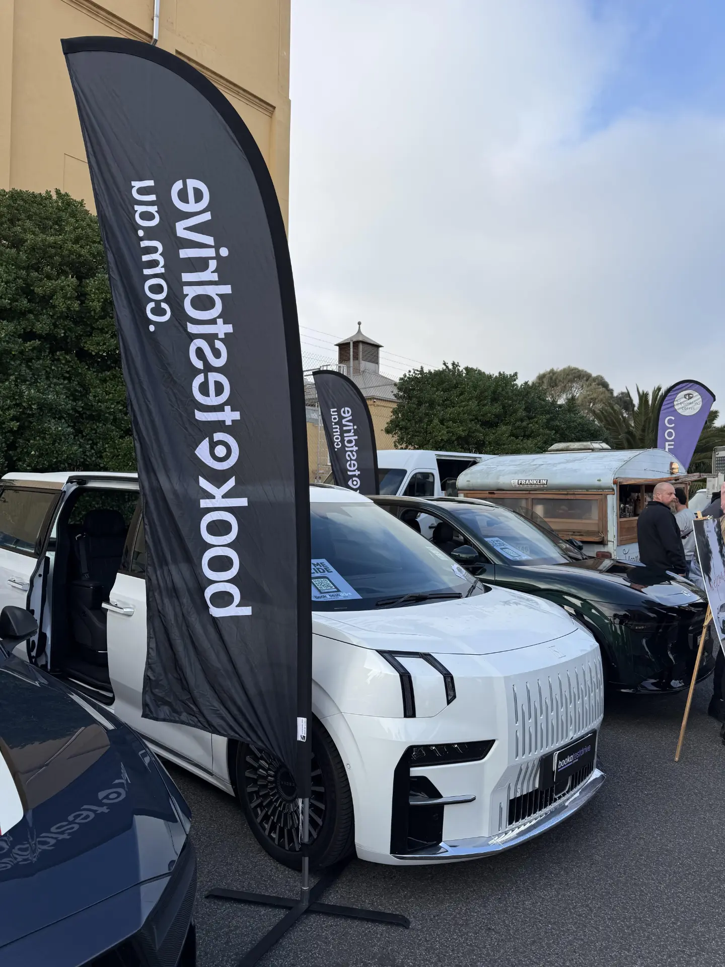 Book a Test Drive flag standing next to new cars on display at a real event